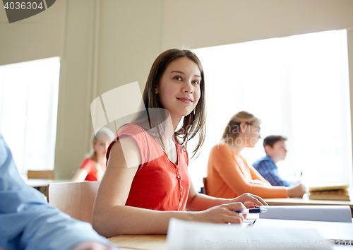 Image of happy student girl with book writing school test