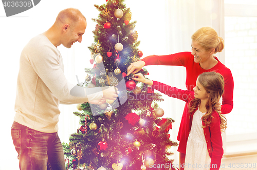 Image of smiling family decorating christmas tree at home