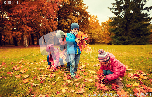 Image of group of children collecting leaves in autumn park