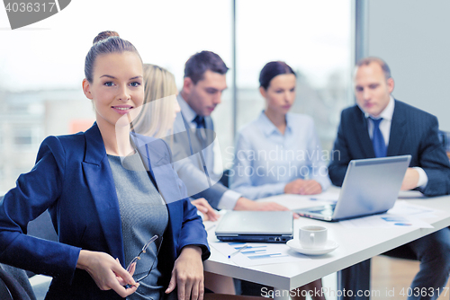 Image of businesswoman with glasses with team on the back