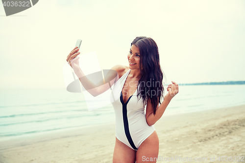 Image of young woman taking selfie with smartphone