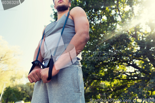 Image of young man exercising with expander in summer park