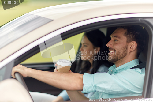 Image of happy man and woman driving in car with coffee