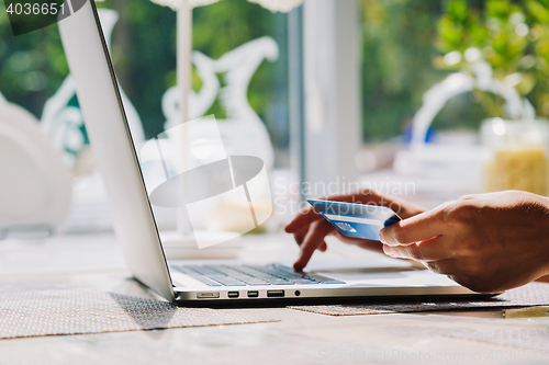 Image of woman using laptop with credit card in hand