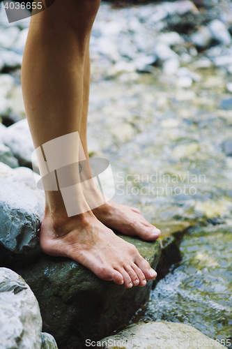 Image of Barefoot woman standing on stone