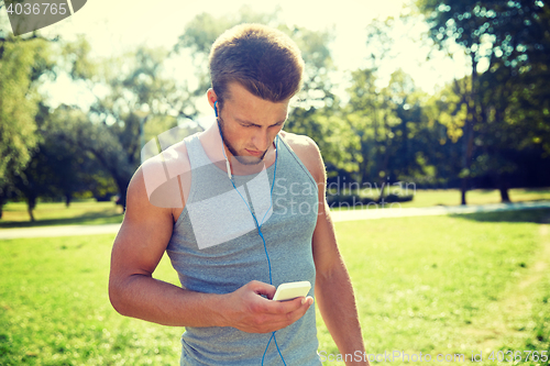 Image of young man with earphones and smartphone at park
