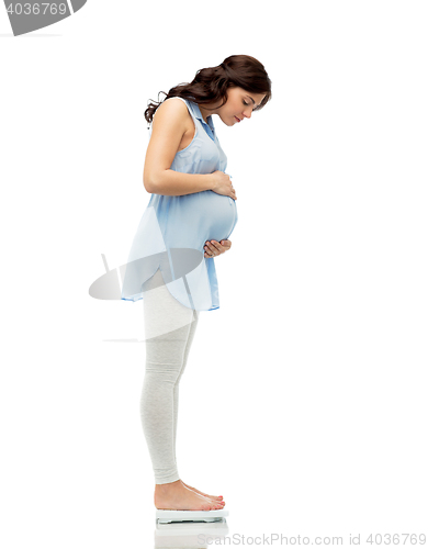 Image of happy pregnant woman measuring weight on scales