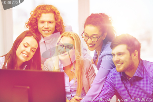 Image of smiling business team looking at computer monitor