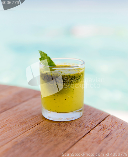 Image of glass of fresh juice or cocktail on table at beach