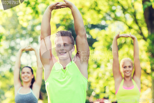 Image of group of friends or sportsmen exercising outdoors