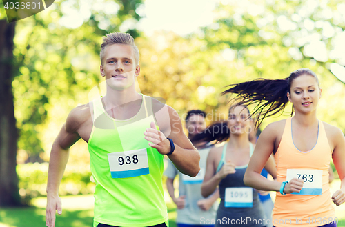 Image of happ young sportsmen racing wit badge numbers