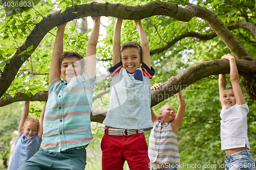 Image of happy kids hanging on tree in summer park