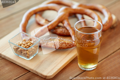 Image of close up of beer, pretzels and peanuts on table