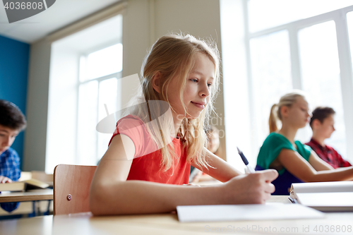 Image of student girl with book writing school test