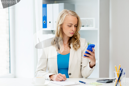 Image of businesswoman texting on smartphone at office