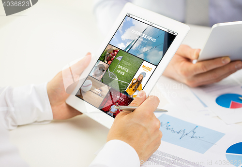 Image of close up of hands with news page on tablet pc