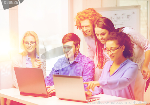 Image of smiling team with laptop computers in office