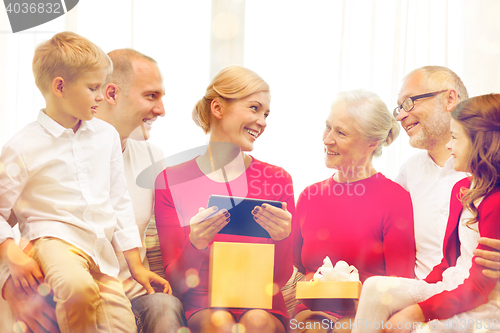 Image of smiling family with tablet pc and gift box at home