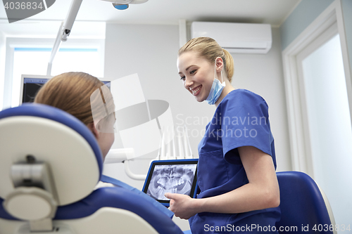 Image of dentist showing x-ray on tablet pc to patient girl