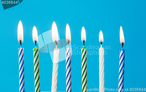 Image of birthday candles burning over blue background