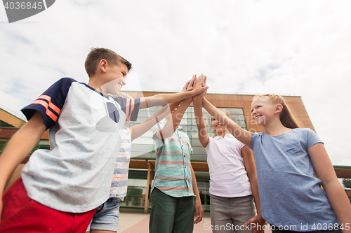 Image of group of children making high five at school yard