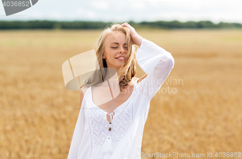 Image of smiling young woman in white dress on cereal field