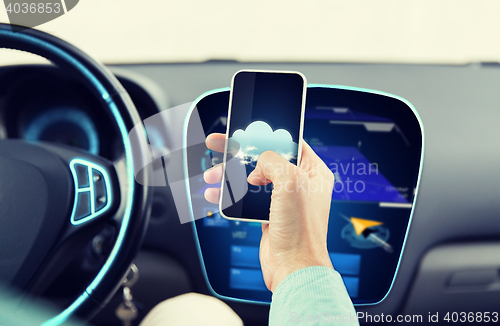 Image of close up of male hand with smartphone driving car