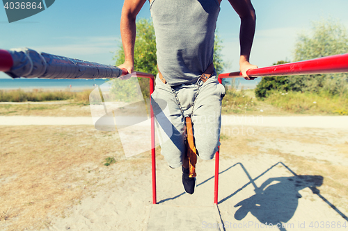 Image of young man exercising on parallel bars outdoors