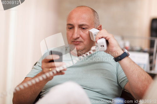 Image of Businessman in the office speaking on two phones