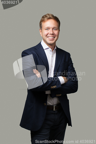 Image of Cheerful businessman with crossed arms isolated on grey