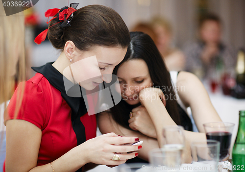 Image of Two stylish women at an event reading sms