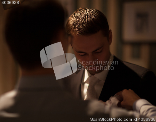 Image of Groomsman fixing boutonniere