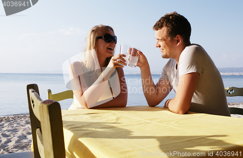 Image of Young couple enjoying drinks at the seaside