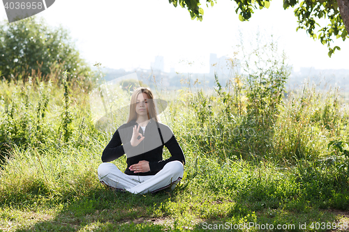 Image of Young woman practicing yoga in the city park