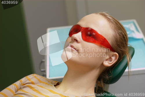 Image of Woman in red safety glasses in dental office