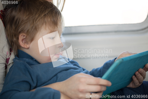 Image of Small boy looking at a tablet in an airplane