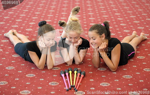 Image of Three girls on the floor looking at Indian clubs