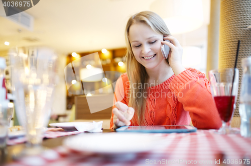 Image of Woman in cafe with touchpad and phone