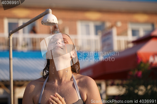 Image of Woman rinsing of at the beach under a shower