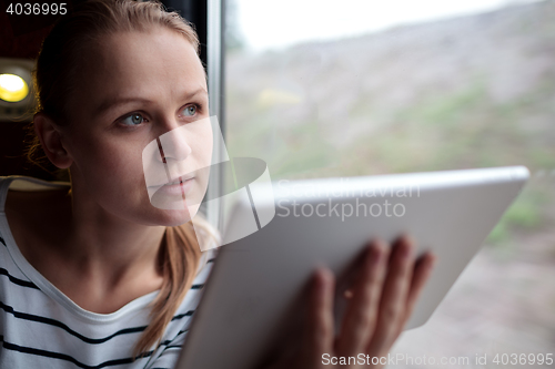 Image of Woman traveling on a train with tablet