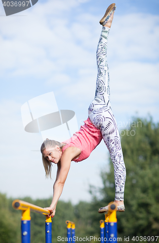 Image of Agile young gymnast balancing on cross bars