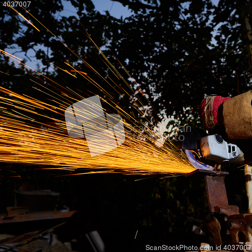 Image of Worker cutting metal with grinder. Sparks while grinding iron