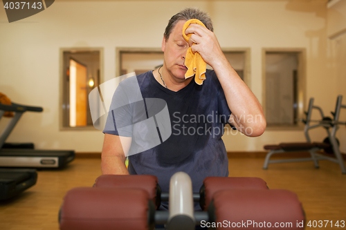 Image of Tired man wiping sweat after workout