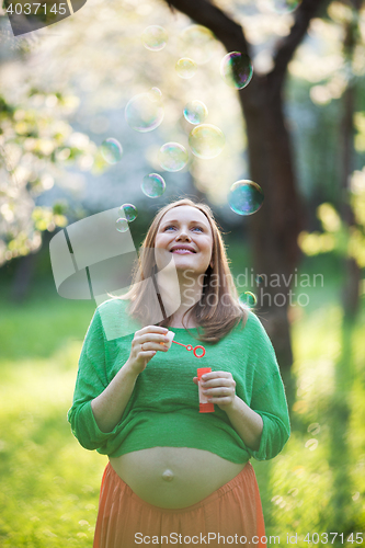 Image of Happy pregnant woman and bubbles outdoor