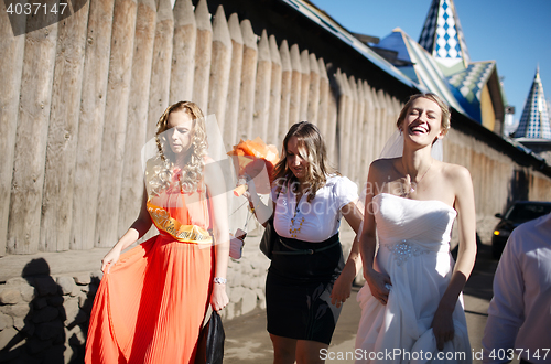 Image of Bride and her bridesmaid walking with friends