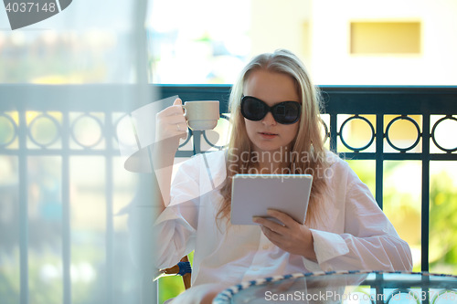 Image of Woman sitting reading a tablet -pc on a balcony