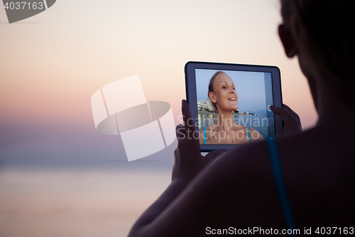 Image of Woman making selfie on resort using pad