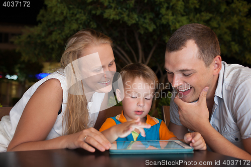 Image of Family of three with pad in outdoor cafe