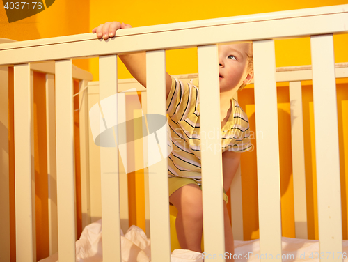 Image of Little boy stands in bed