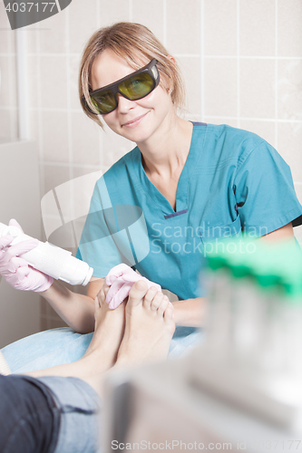 Image of Smiling cosmetician working with laser to treat feet